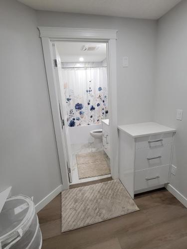a white bathroom with a shower and a toilet at Cozy and Modern Suite - Your Home Away from Home! in Calgary