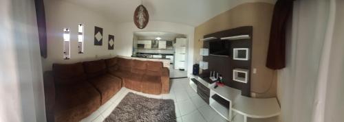 Una sala de estar con un sofá y una cocina. en Casa praia, en Barra Velha