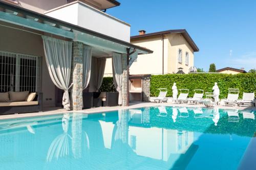 a swimming pool with chairs and a house at Villa Giuly in Sirmione