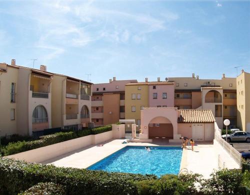 deux chiens assis dans une piscine devant des bâtiments dans l'établissement ALOA Joli 3 Pièces piscine proche plage Richelieu Cap d'Agde, au Cap d'Agde