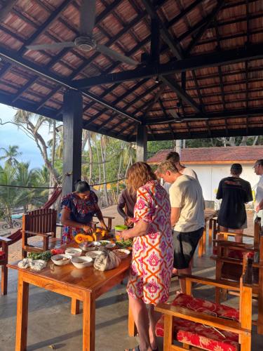 a group of people standing around a table with food at Kudah Bay Surf Camp in Arugam Bay