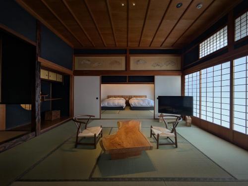 a room with a bed and a tv and a couch at 古民家ラグジュアリーホテル 金井西洋館 in Sado