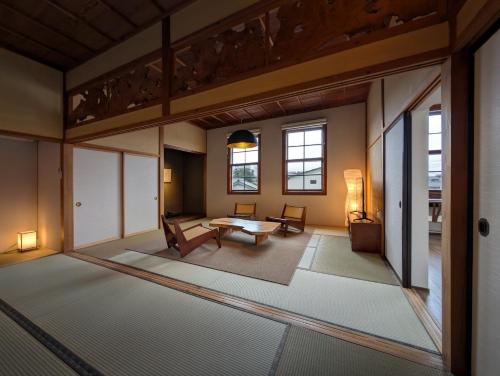 a large living room with a table and chairs at 古民家ラグジュアリーホテル 金井西洋館 in Sado