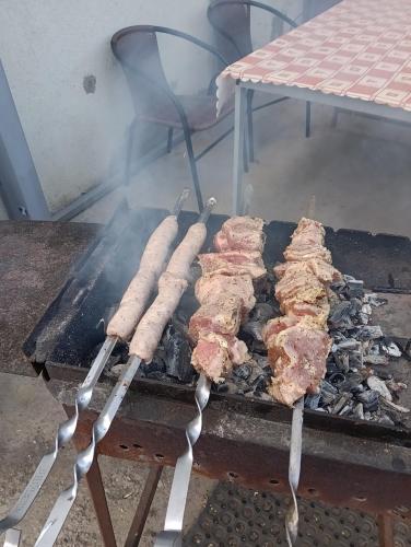 a group of meat cooking on a grill with tongs at Apartment hotels parking akaciju1 in Vilnius