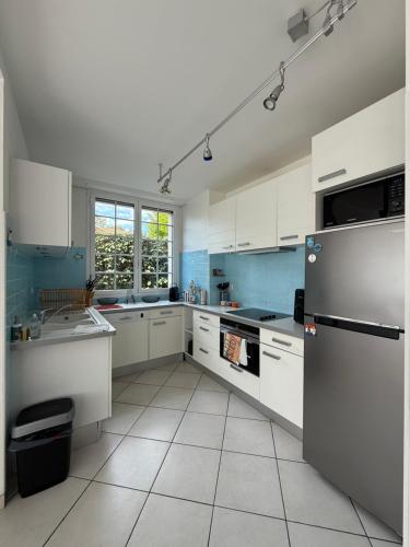  La cuisine est équipée de placards blancs et d'un réfrigérateur. dans l'établissement Maison à côté de la Plage Le Moulleau Arcachon, à Arcachon