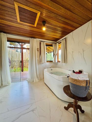 a large bathroom with a tub and a wooden ceiling at Pousada Villa Monte Verde in Monte Verde