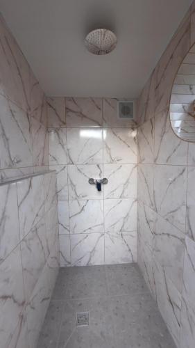 a bathroom with a shower with white marble walls at Otdykh u moria in Fontanka