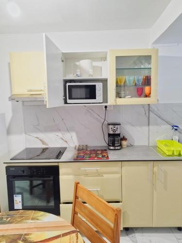 a kitchen with white cabinets and a microwave at Chez laRosy in Le Vauclin