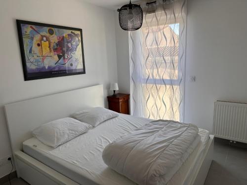 - un lit blanc dans une chambre avec fenêtre dans l'établissement Superbe T3 proche remparts 2 places de parking, à Aigues-Mortes