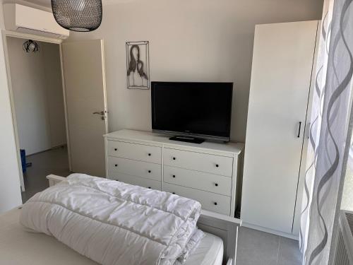 - un salon avec une télévision et une commode blanche dans l'établissement Superbe T3 proche remparts 2 places de parking, à Aigues-Mortes