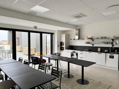 - une cuisine avec des tables et des chaises dans une pièce dans l'établissement We Live Inn Sharies Reims A405, à Reims