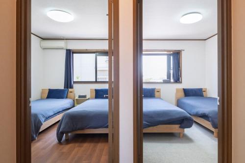 松本市にあるVacation Rental NAGISAのベッドルーム1室(ベッド3台、窓2つ付)