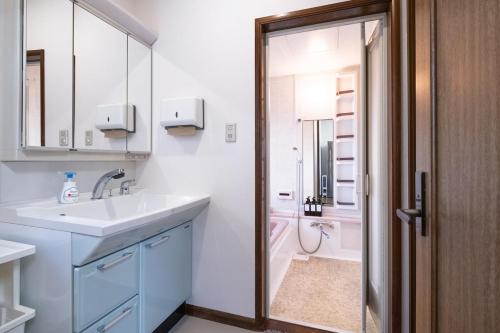 松本市にあるVacation Rental NAGISAの洗面台とシャワー付きの白いバスルーム