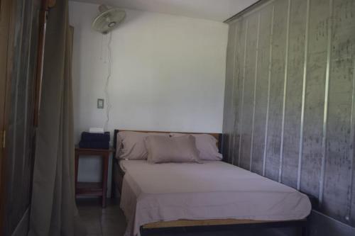 a small bed in a room with a wall at Coconut Lodge Pavones in Pavones