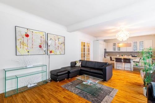 un salon avec un canapé noir et une cuisine dans l'établissement GuestReady - Luxury Living in the Heart of Paris, à Paris