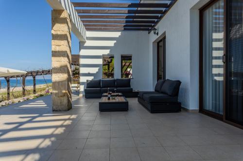 a patio with chairs and a table and the ocean at Kallisti Beach & Spa Villa - A Luxury Seaside Retreat in Lachi