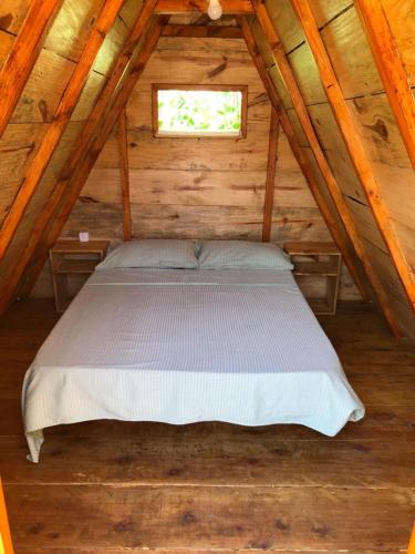 a bed in a wooden cabin with a window at Pousada 4 Elementos Guaruja in Guarujá