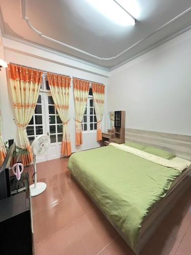 a bedroom with a large green bed and windows at Nhà Bi'x in Da Lat