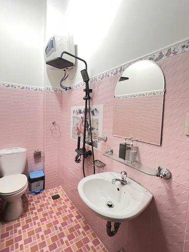 a pink bathroom with a sink and a mirror at Nhà Bi'x in Da Lat