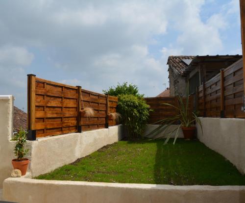 a backyard with a wooden fence and green grass at Le petit coin caché in Montreuil-Bellay