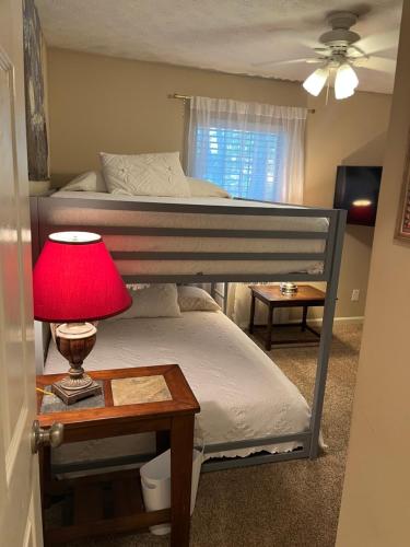 a bedroom with two bunk beds and a table with a lamp at Classic City 3 bedroom 2 bath condo with deck close to UGA, Five Points, and Memorial Park in Athens in Athens