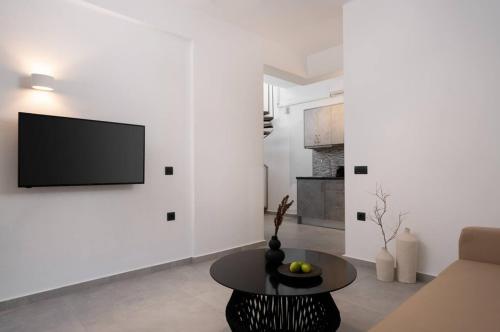 Una sala de estar con un televisor en una pared blanca. en Swell Suites, Santorini, en Vourvoúlos