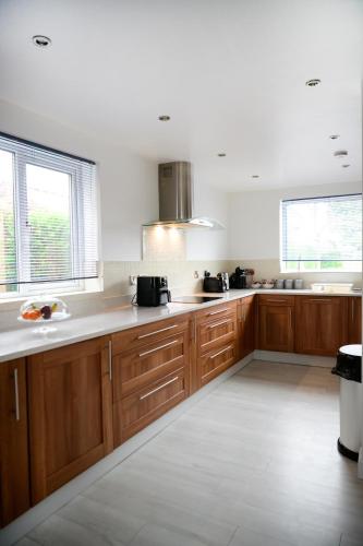 a kitchen with wooden cabinets and white counter tops at Strelley house 4 , Perfect for business trip & Families holiday or working proffesionals-5 min from M1 J25 , 500MB Wi-Fi , Netflix , Fully equiped kitchen , Asda supermarket 5 min walk , Free Secure parking with CCTV ,available monthly deals in Nottingham
