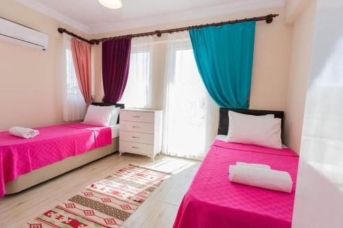 two beds in a room with pink and blue curtains at Villa carin in Ortaca