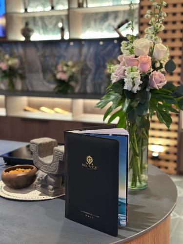 a book sitting on a table with a vase of flowers at MantaHost Hotel in Manta