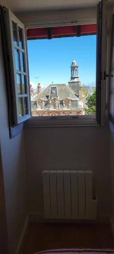 une fenêtre avec vue sur un bâtiment et un phare dans l'établissement Vue mer - Superbe Appartement à 50 m de la plage et du centre ville, à Cabourg