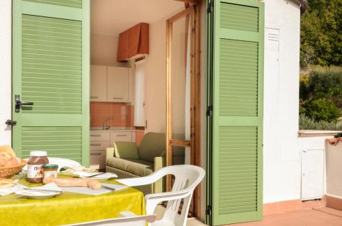 a patio with green shutters and a table and chairs at Residence Dei Fiori in Pietra Ligure