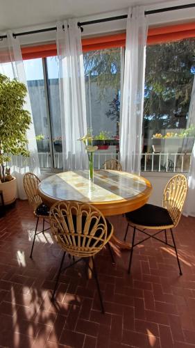 une table et des chaises dans une pièce avec des fenêtres dans l'établissement Lumière, à La Ciotat