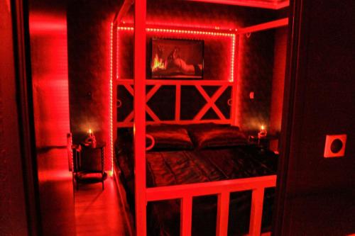 a red room with a bed with a wooden frame at Le baiser 2 Love room du plaisir interdit in Saint-Arnoult