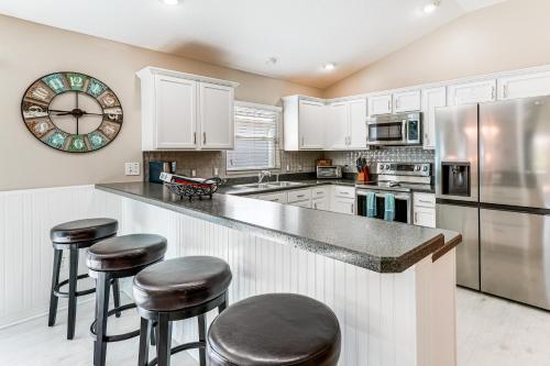 a kitchen with white cabinets and bar stools at Village of Collier Retreat with Golf Cart and Lanai! in The Villages