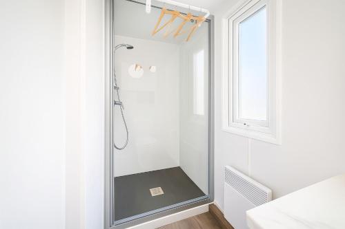 une douche avec une porte vitrée dans une salle de bain dans l'établissement Trois-lets - Evasion et Confort au Bois Masson, à Saint-Jean-de-Monts