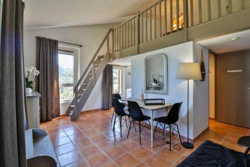 a living room with a table and chairs and a staircase at Le Domaine de la mer - Appartements de plage dans un cadre enchanteur in Hyères