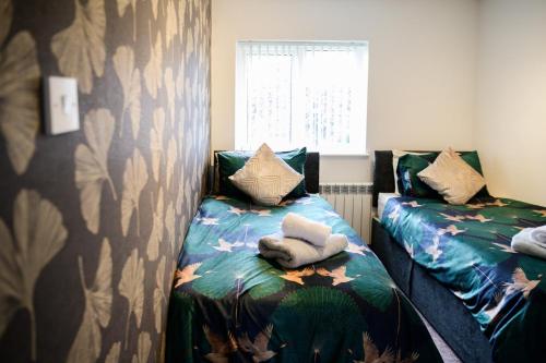 two beds sitting next to each other in a room at Strelley house 4 , Perfect for business trip & Families holiday or working proffesionals-5 min from M1 J25 , 500MB Wi-Fi , Netflix , Fully equiped kitchen , Asda supermarket 5 min walk , Free Secure parking with CCTV ,available monthly deals in Nottingham