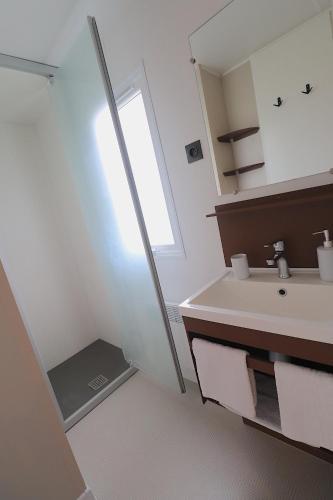 une salle de bain blanche avec un lavabo et un miroir dans l'établissement Mobil Home Confort sur parcelle privée - 2 chambres - Ajaccio, à Ajaccio