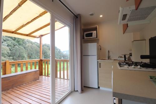 une cuisine avec une porte coulissante en verre menant à une terrasse dans l'établissement Mobil Home Confort sur parcelle privée - 2 chambres - Ajaccio, à Ajaccio