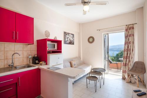 a kitchen with red cabinets and a table with a microwave at Agrili Sea View in Corfu