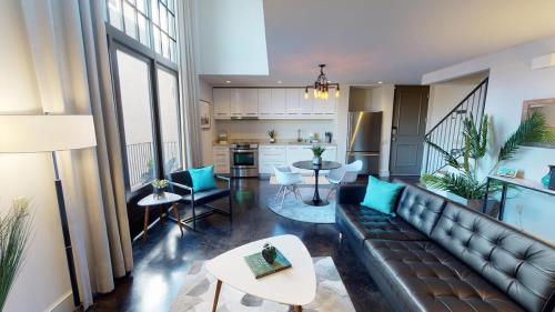 a living room with a leather couch and a kitchen at Heart of Cloverdale Loft - Free Gated Parking in Montgomery