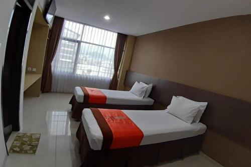 two beds in a hotel room with a window at Hotel Bumi Makmur Indah in Bandung