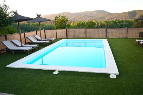 a swimming pool on a lawn with chairs and umbrellas at Villa Escutia in Cazalla de la Sierra