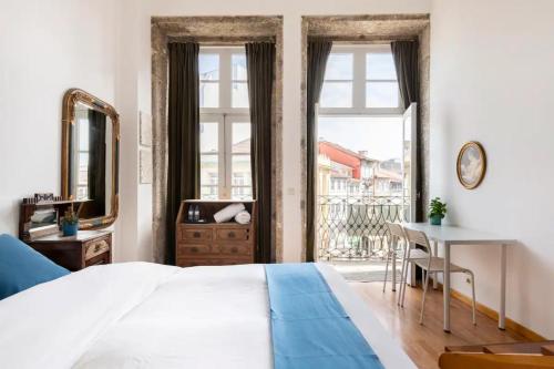 a bedroom with a bed and a desk and a window at Sir Manuel Guest House - Unidade Centro Histórico in Braga