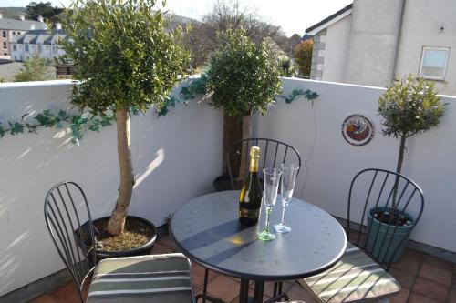 een tafel en stoelen met een fles wijn op een balkon bij Marine Haven in Ballycastle