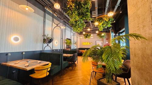 Exclusive 1BR Apartments in ONE Cotroceni في بوخارست: مطعم بالطاولات والكراسي والنباتات الفخارية