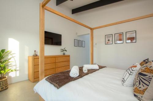 a bedroom with a large white bed with a wooden frame at Giraffe Oasis - Kruger Luxury Family Villa in Marloth Park