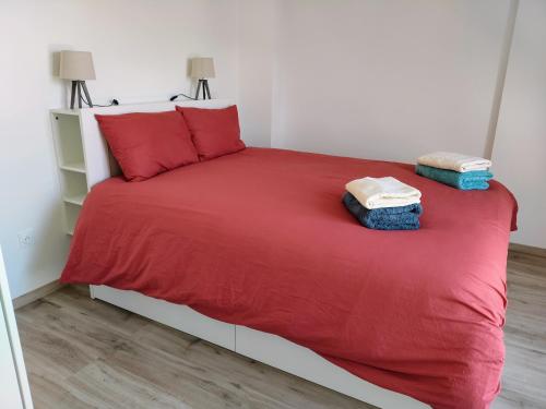 a bedroom with a red bed with two towels on it at Appartement neuf, calme et ensoleillé in Cabourg