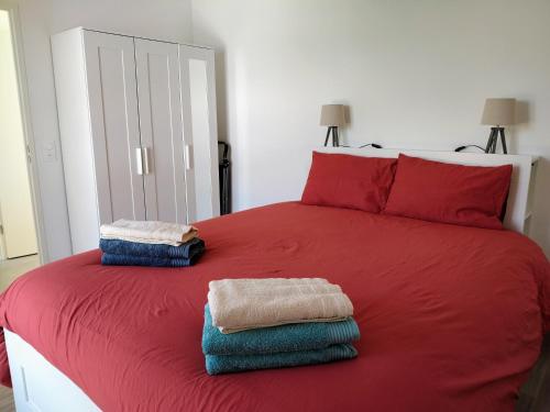 a red bed with two towels on top of it at Appartement neuf, calme et ensoleillé in Cabourg