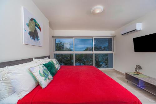 a bedroom with a red bed with a large window at Sanctuary by Playa Caracol Frente al Mar in Punta Chame